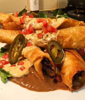 Delicious Chile con queso topped with jalapeños, tomatoes, and creamy sauce, served with crispy taquitos.
