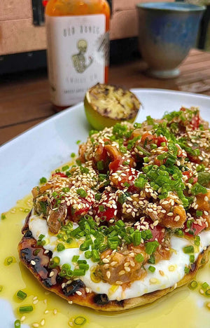 Recipe | Yellowfin Tuna Tartare & Yoghurt Flatbreads served on a plate with a bottle of Old Bones Chilli Co Smoked Garlic Chilli sauce in the background