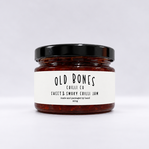 A glass jar of Old Bones Chilli Co Sweet & Smoky Chilli Jam 200g with a black lid and a white label, set against a clean white background.